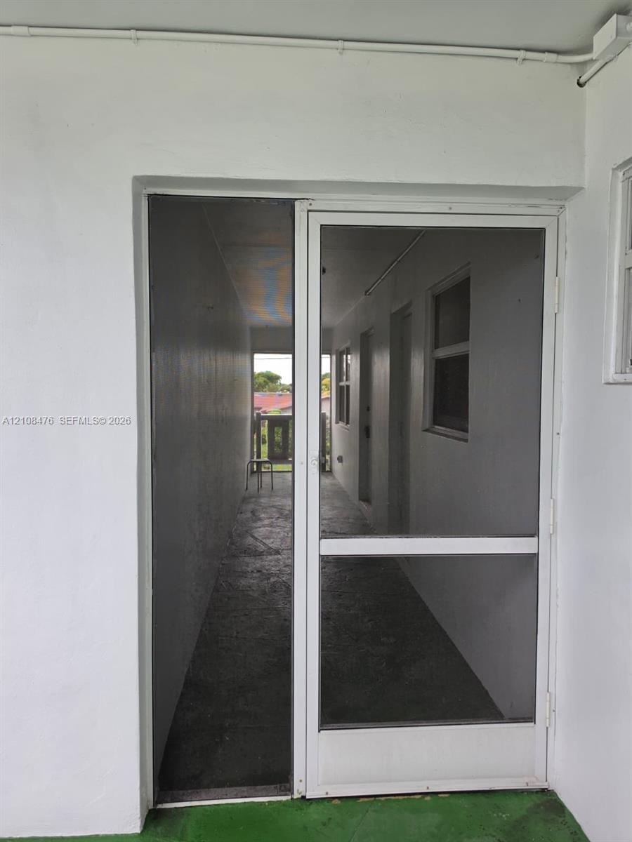 White aluminum frame screen door featuring a glass-inset panel and secure latch hardware