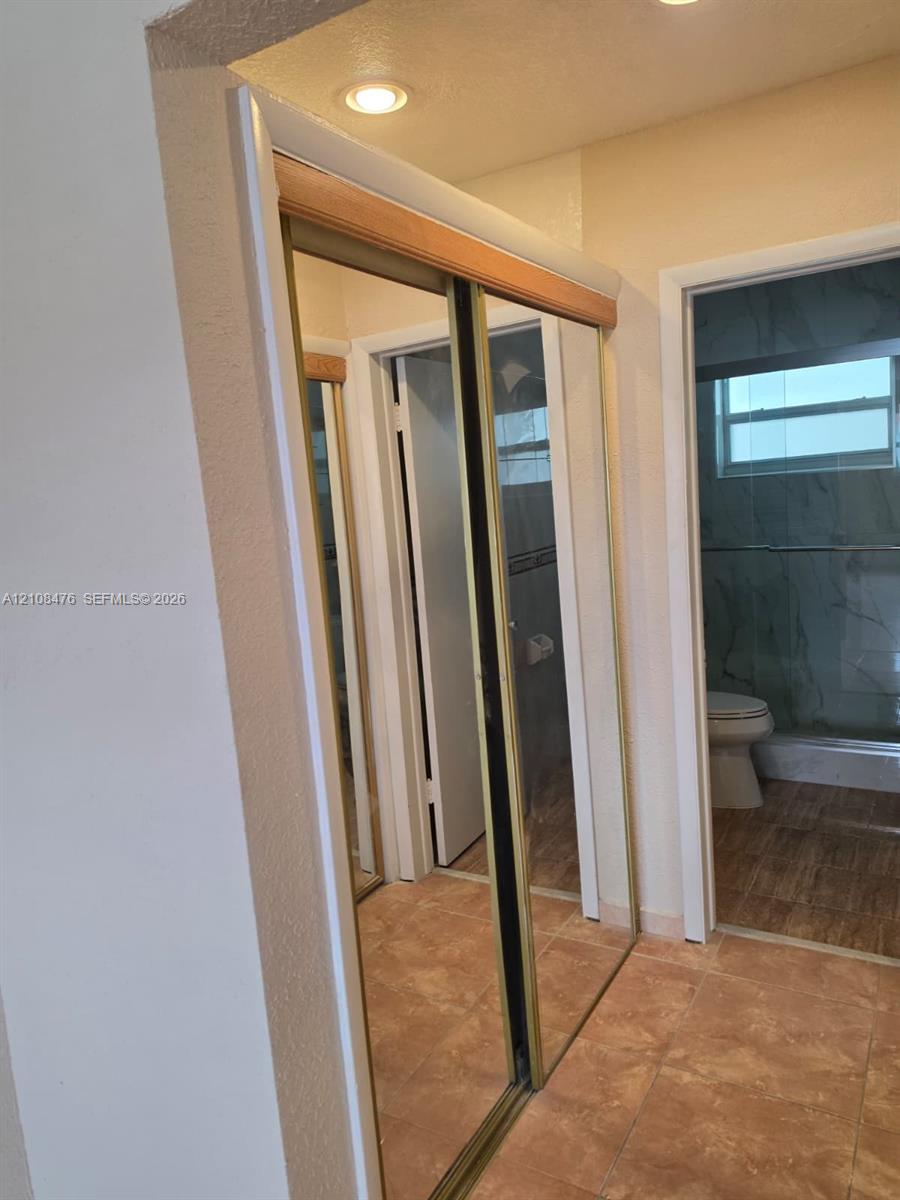 Sliding mirrored closet doors with gold-tone frames and recessed ceiling lighting