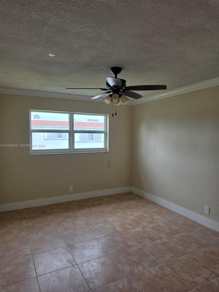 Room featuring tile flooring, crown molding, and a multi-light ceiling fan