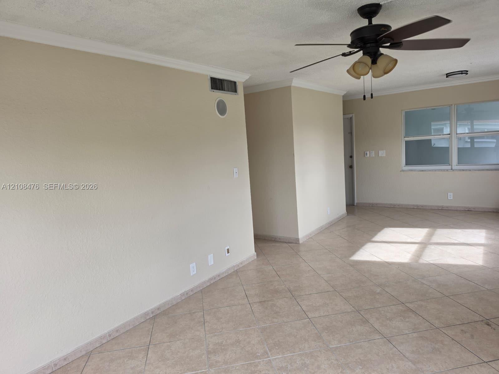 Neutral-toned interior featuring ceramic tile flooring, crown molding, and a ceiling fan with integrated lighting Neutral-toned interior featuring ceramic tile flooring, crown molding, and a ceiling fan with integrated lighting