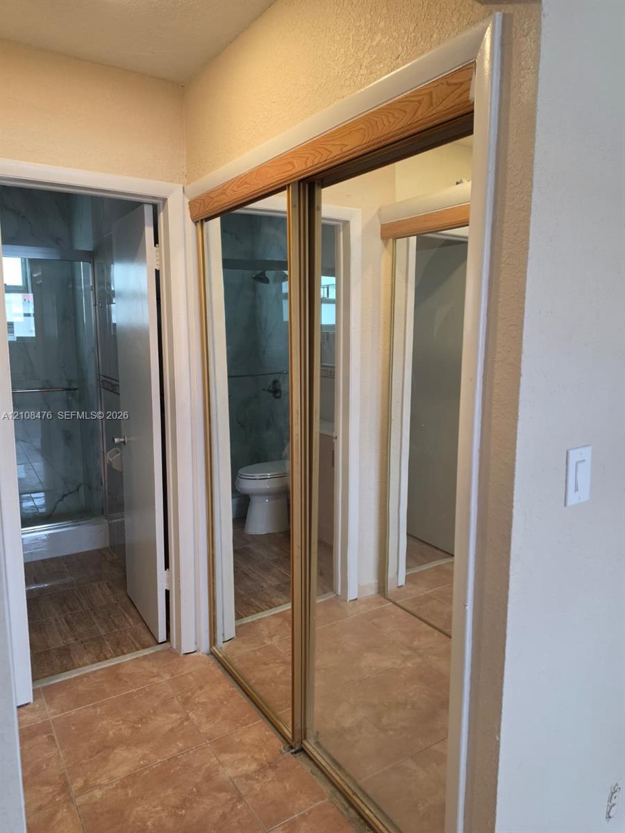 Floor-to-ceiling sliding mirrored closet doors with wood-toned trim and tile flooring