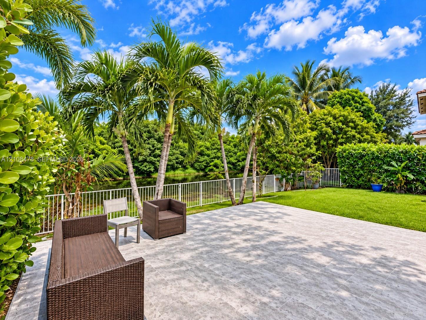 Stucco exterior featuring arched windows, large-format tile patio, metal-frame gazebo, and built-in sliding glass doors