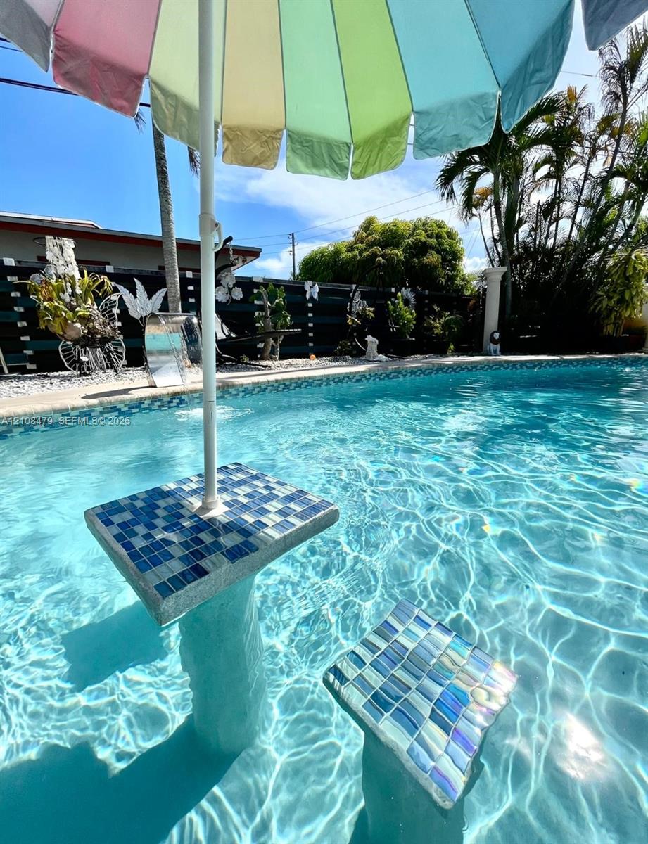 In-ground swimming pool featuring a tiled, built-in pedestal table and submerged seating with iridescent mosaic finish In-ground swimming pool featuring a tiled, built-in pedestal table and submerged seating with iridescent mosaic finish