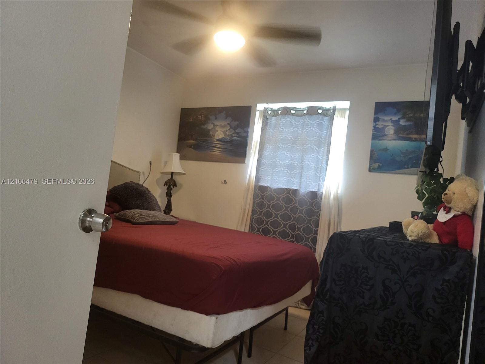 Bedroom interior featuring a ceiling fan with integrated lighting and window treatments