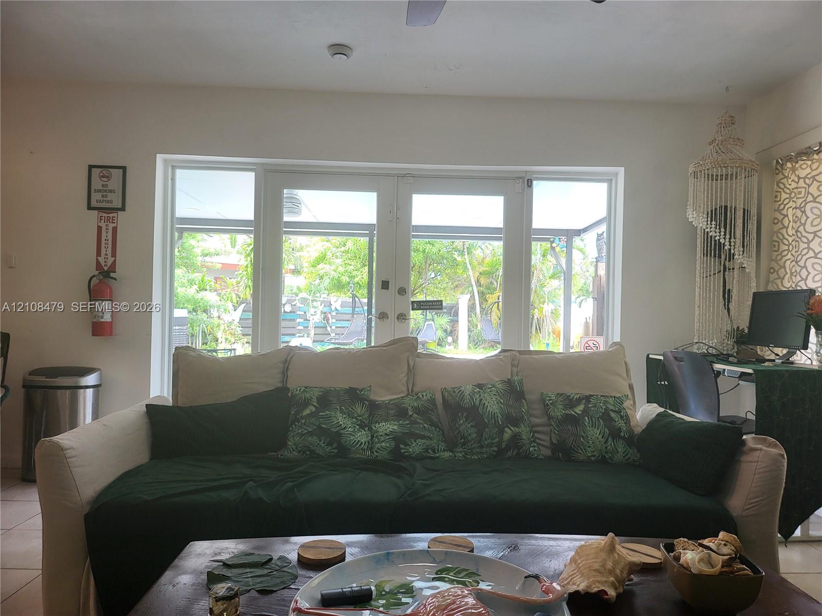 Double glass panel doors with flanking sidelights, tile flooring, and integrated ceiling fan