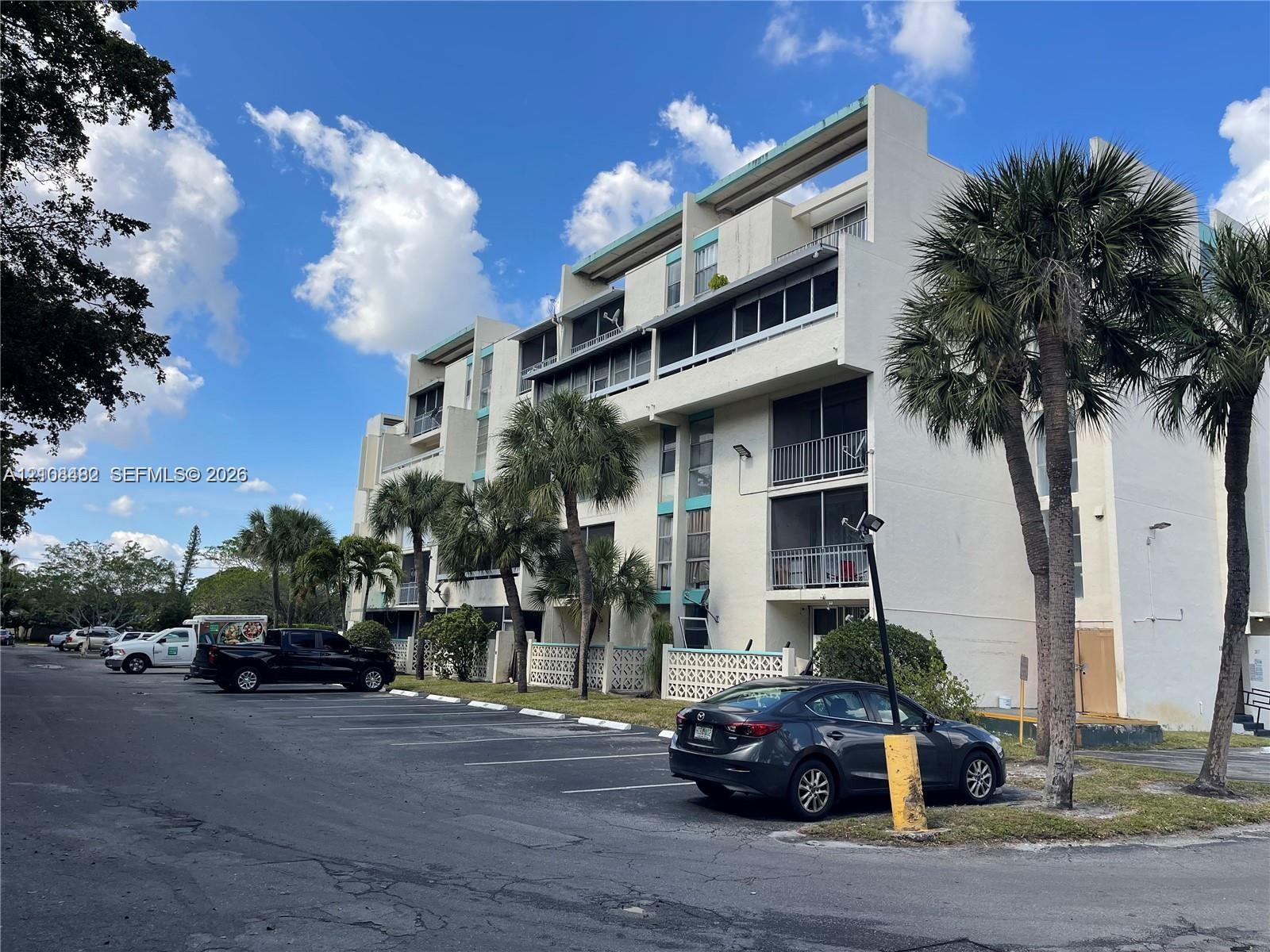 Multi-story residential building exterior featuring concrete facade, screened balconies, and decorative lattice screening Multi-story residential building exterior featuring concrete facade, screened balconies, and decorative lattice screening