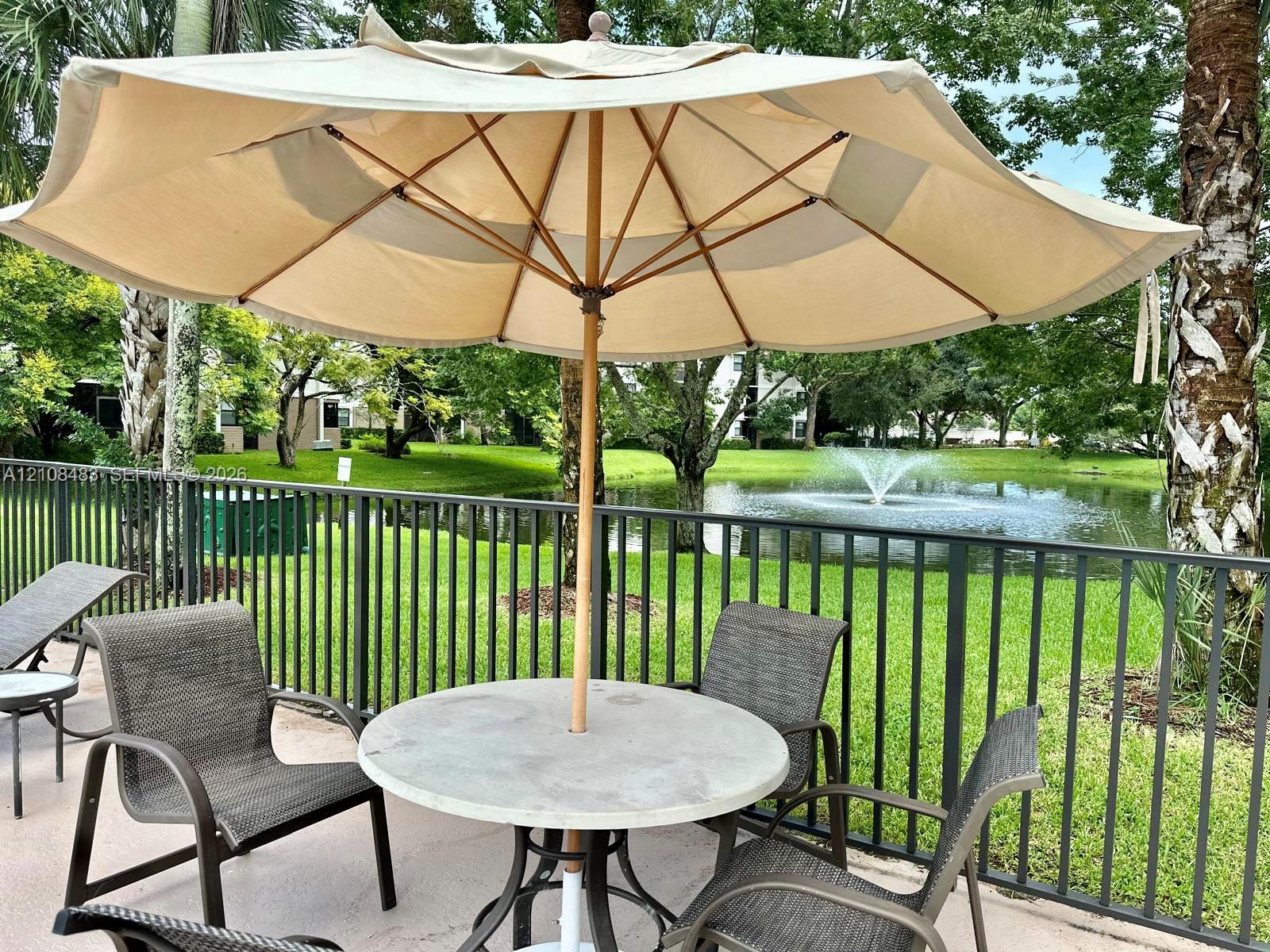 Outdoor patio area featuring a concrete deck, dark metal perimeter fencing, and water feature backdrop