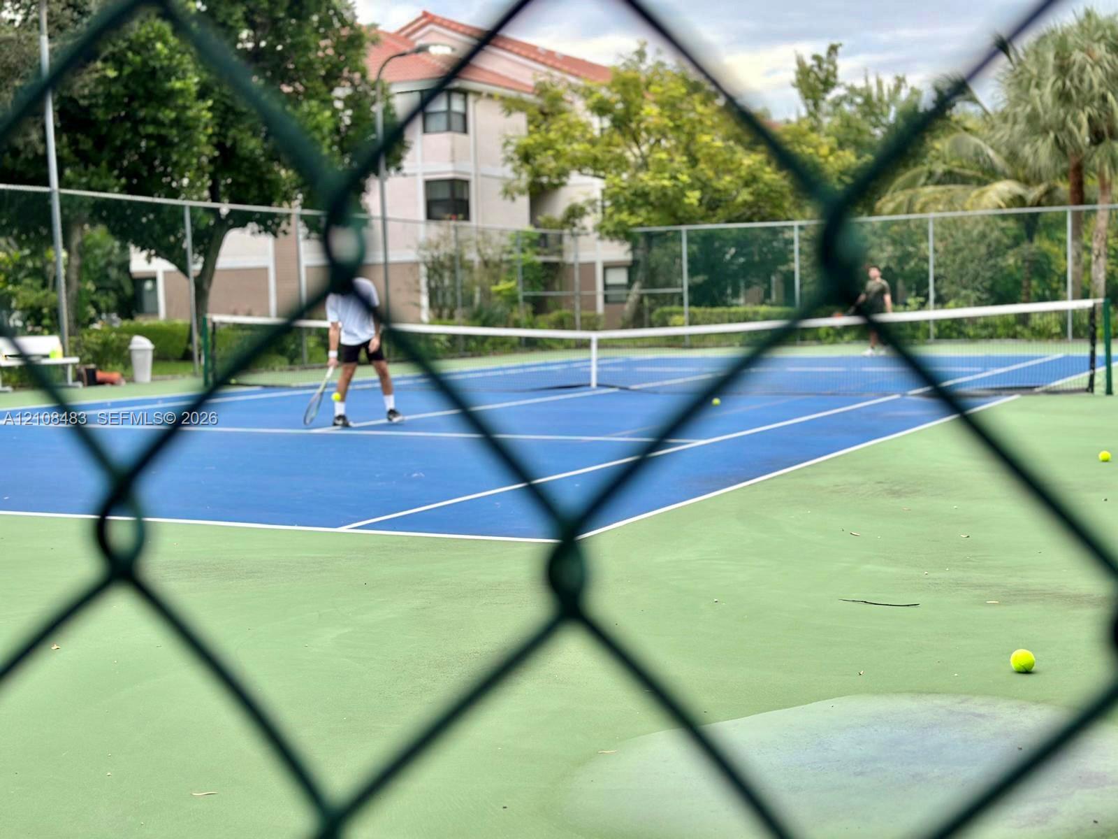 Tennis court with hard-surface playing area, net, and perimeter chain-link fencing