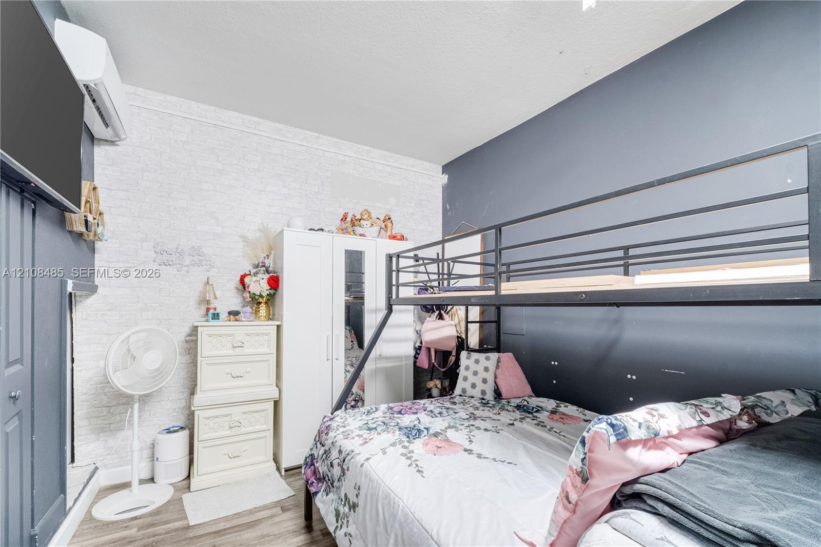 Textured white brick-pattern wall, high-contrast dark blue accent walls, wood-finish flooring, and wall-mounted climate control unit