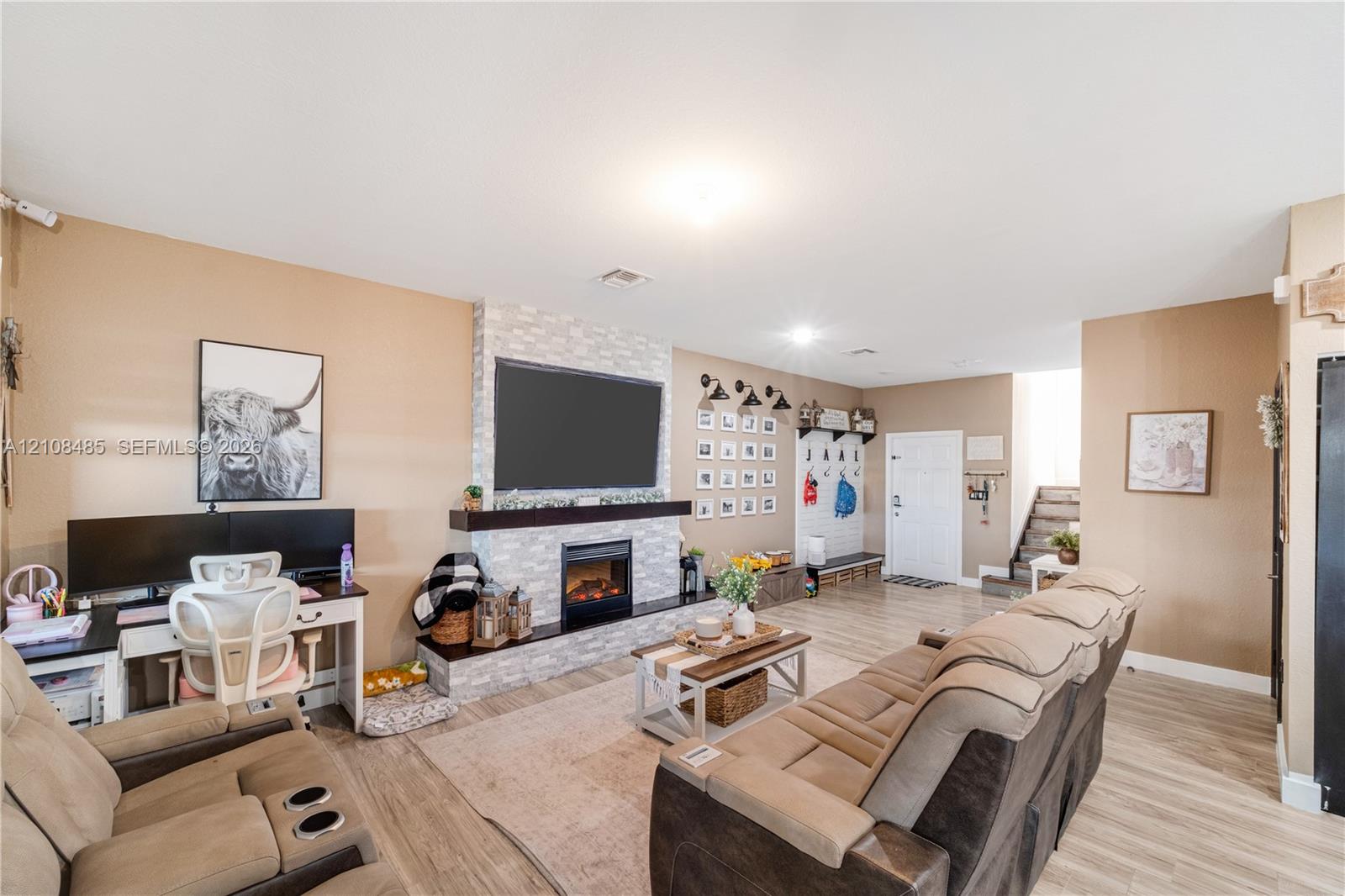 Living area featuring stone-clad fireplace, dark wood mantel, recessed lighting, and wood-finish flooring