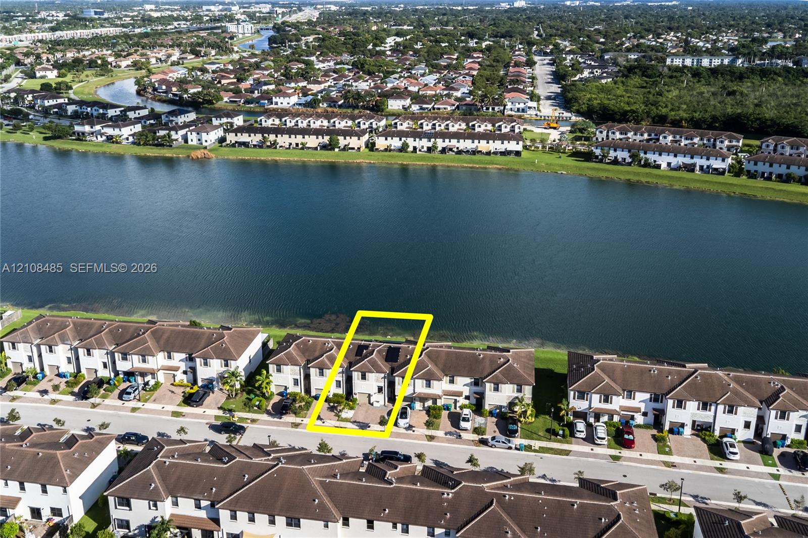 Aerial perspective of a multi-story townhome featuring a paved driveway and direct water frontage along a large lake
