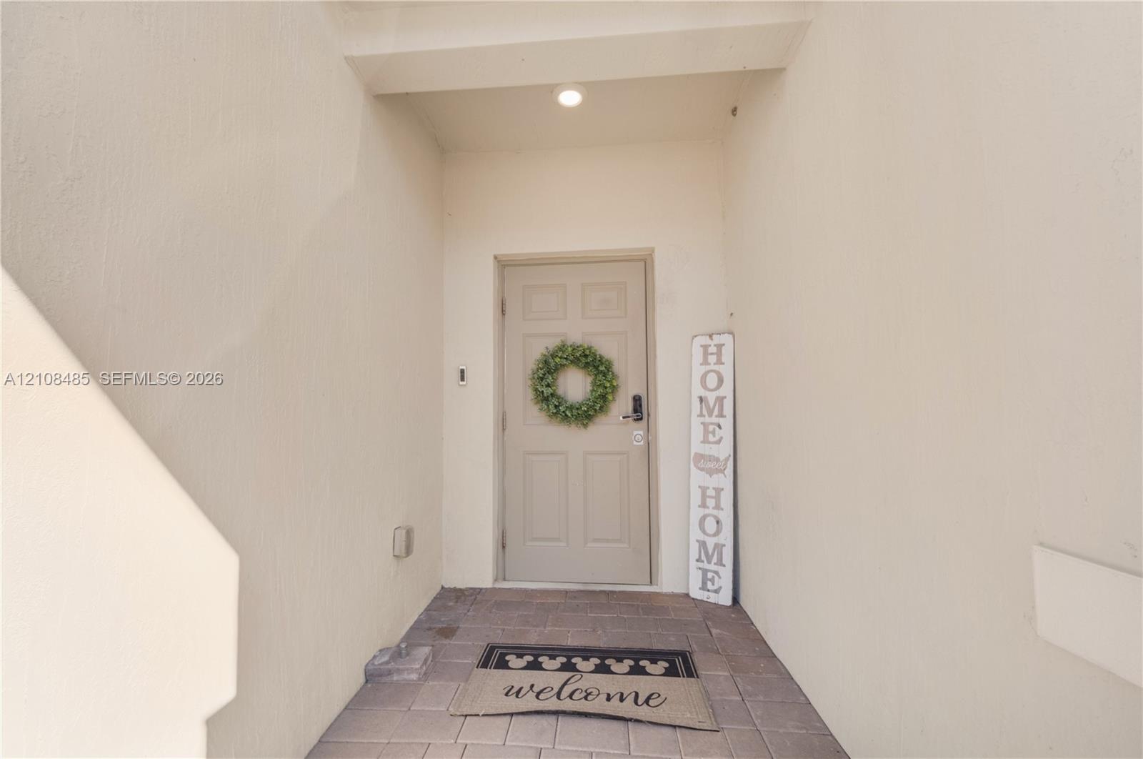 Covered entryway featuring smooth wall finishes, recessed lighting, and paver stone flooring