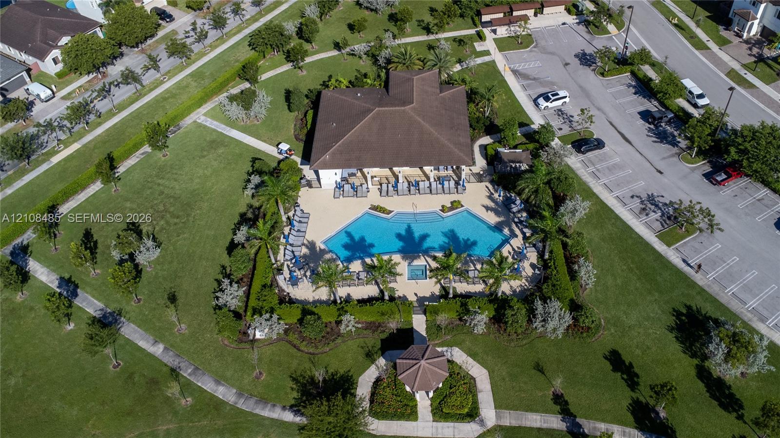Community recreation center featuring an outdoor swimming pool, spa, surrounding paved deck, covered gazebo, and landscaped grounds
