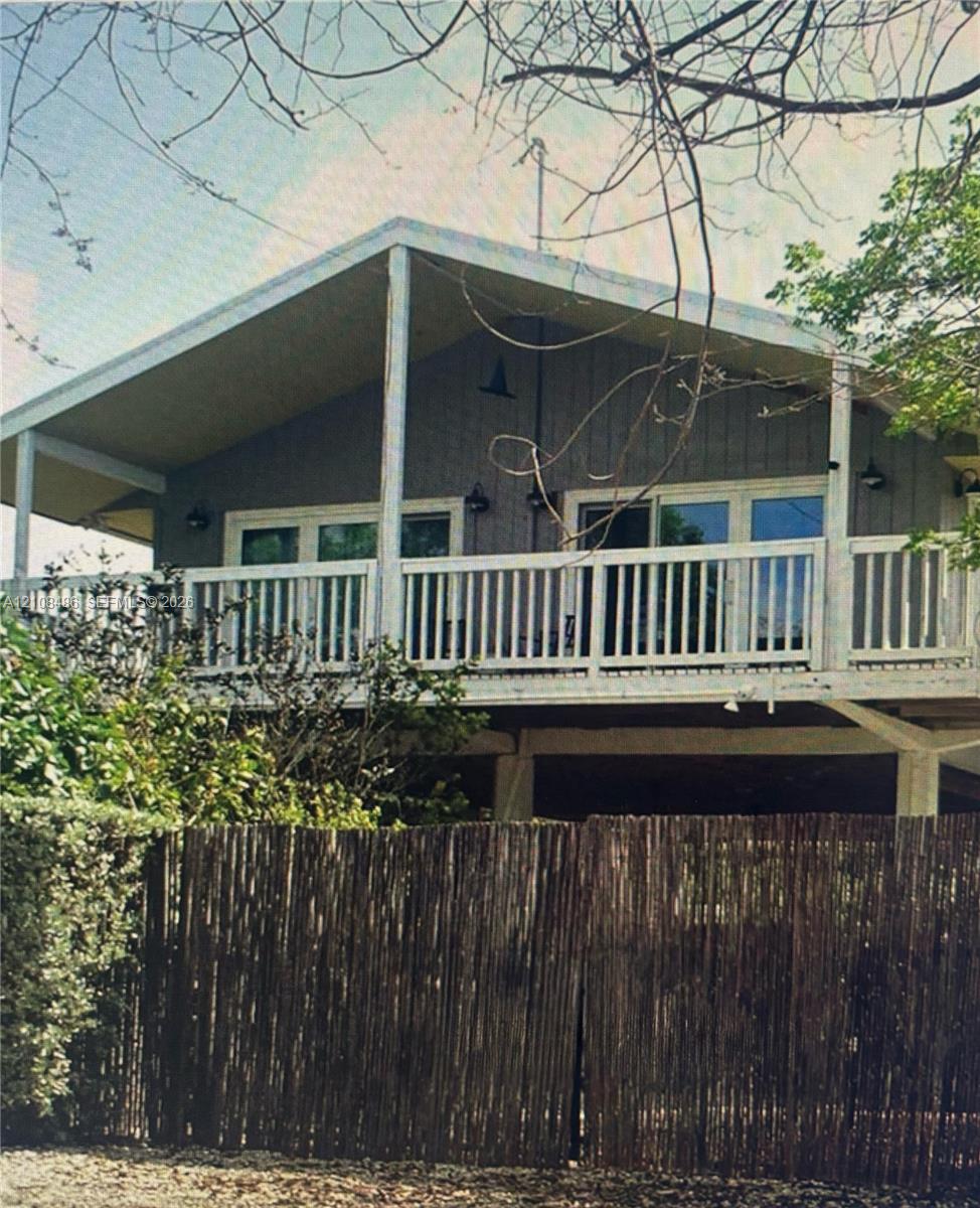 Elevated exterior featuring a pitched roofline, vertical wood-panel siding, a railed balcony, and wall-mounted exterior light fixtures