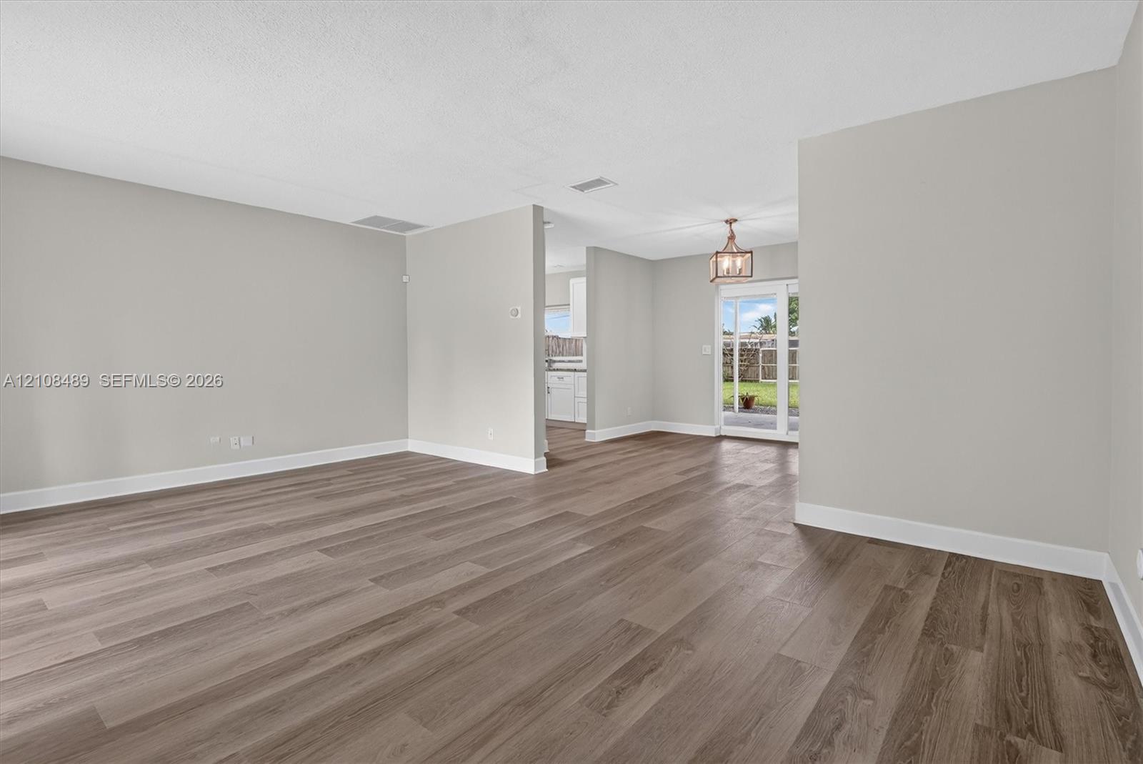 Neutral-toned interior featuring wood-finish flooring, a multi-pane glass door, and a geometric pendant light fixture