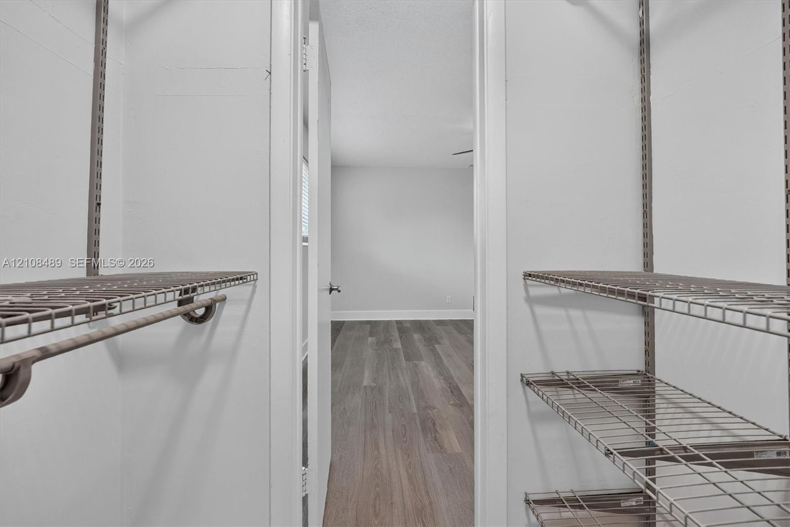 Storage area featuring adjustable metal wire shelving, hanging rods, and wood-finish flooring