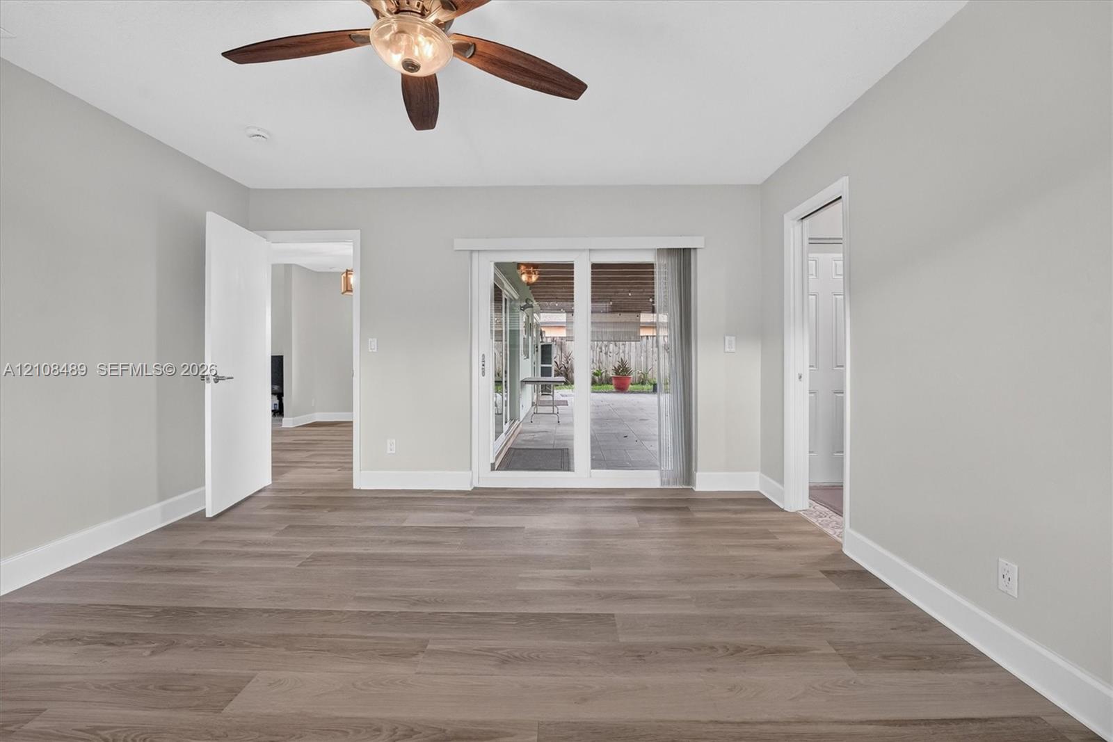 Interior space featuring wood-finish flooring, a ceiling fan with integrated lighting, and sliding glass doors