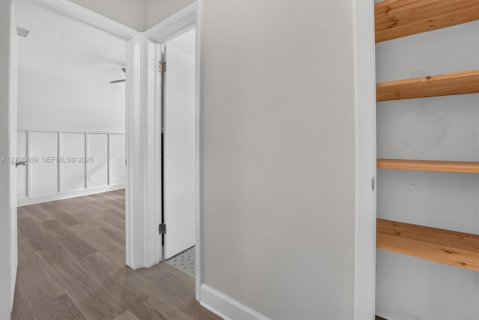 Built-in wood shelving, wood-finish flooring, and white wall paneling