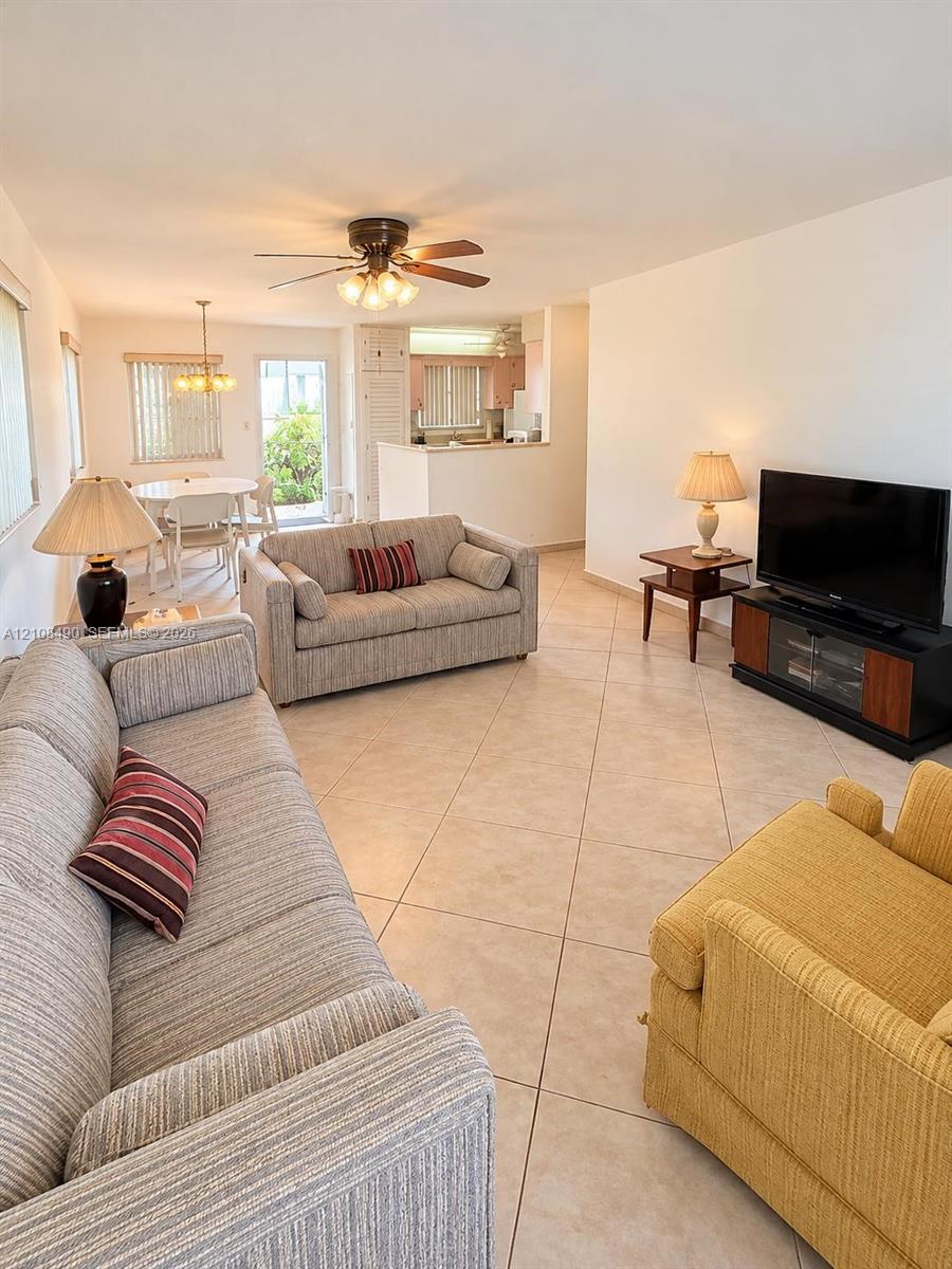 Open-concept interior featuring large-format ceramic tile flooring, a ceiling fan with integrated lighting, and a glass-paneled exterior door