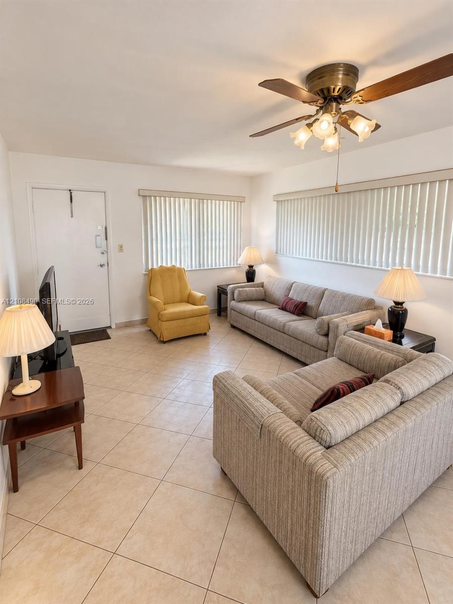 Ceramic tile flooring, neutral wall finishes, vertical window blinds, and a multi-blade ceiling fan with integrated lighting