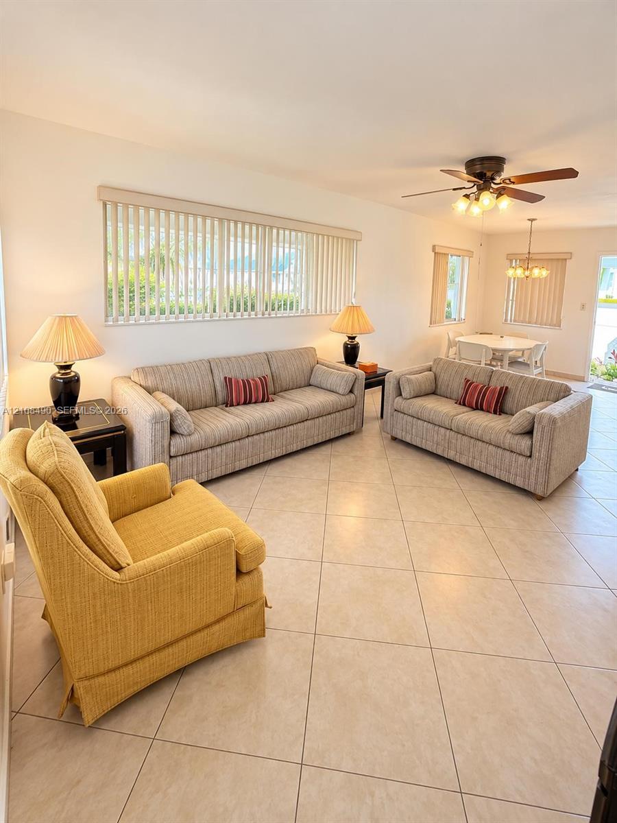 Neutral ceramic tile flooring, ceiling fan with integrated lighting, and vertical window blinds