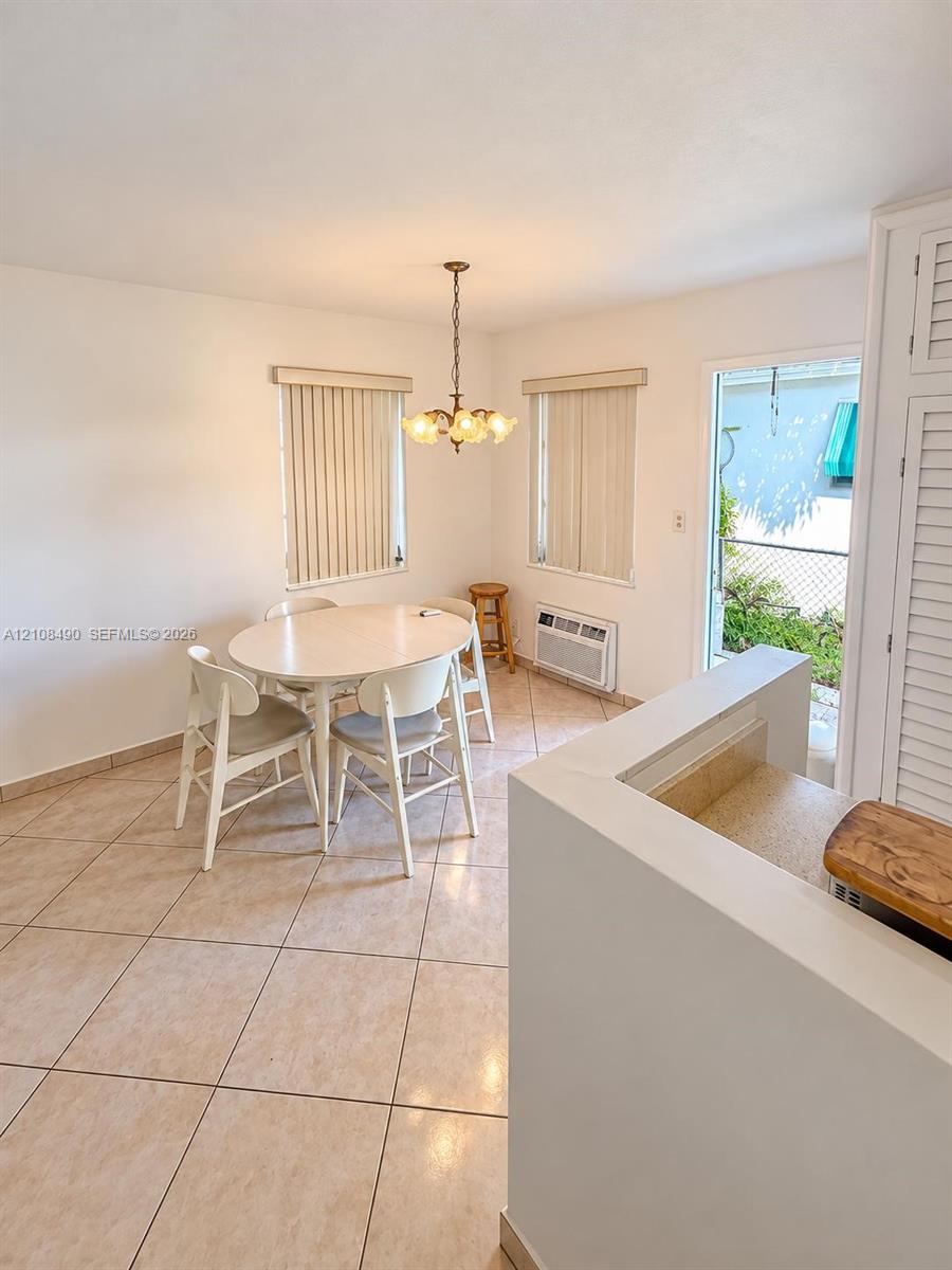 Ceramic tile flooring, multi-light hanging chandelier, built-in louvered cabinetry, and exterior access via a glass-panel door