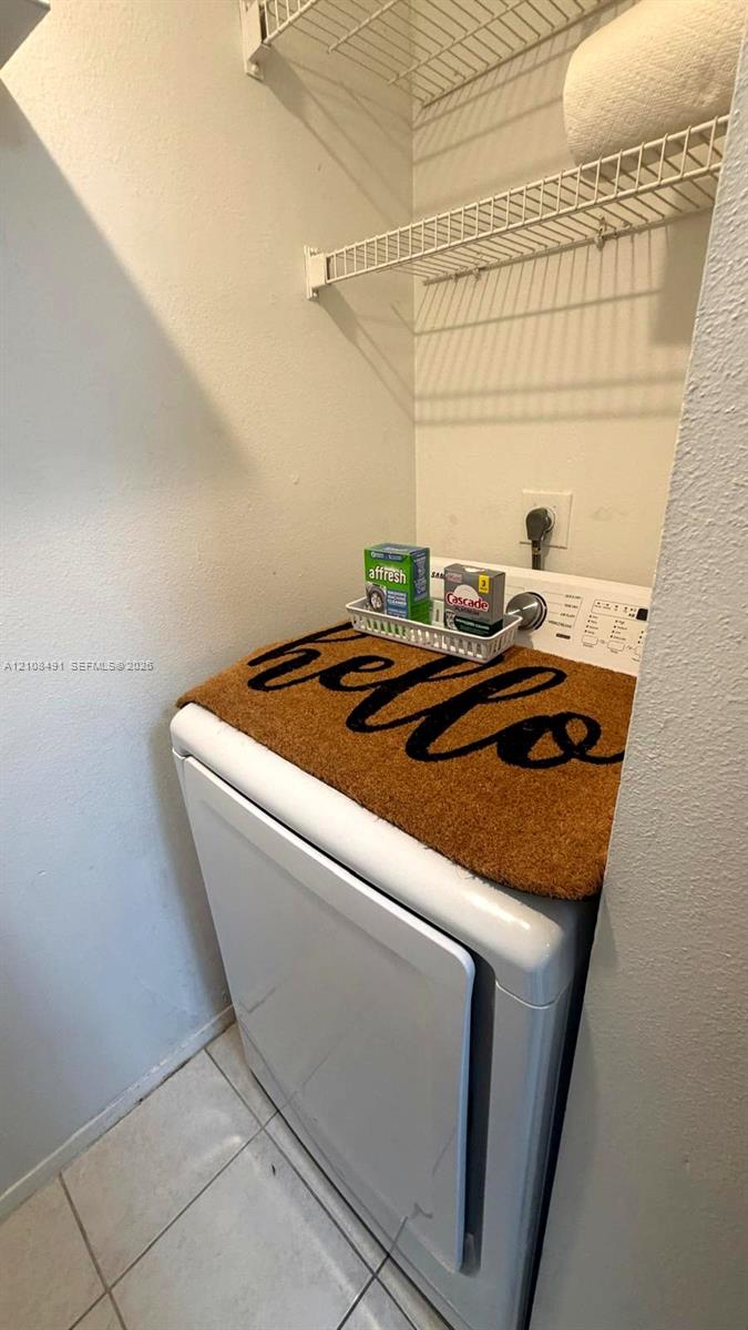 Laundry area featuring tile flooring and dual-tier wire shelving