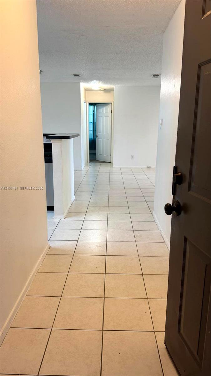 Neutral-toned tile flooring, recessed ceiling lighting, and a partial breakfast bar featuring a dark countertop Neutral-toned tile flooring, recessed ceiling lighting, and a partial breakfast bar featuring a dark countertop