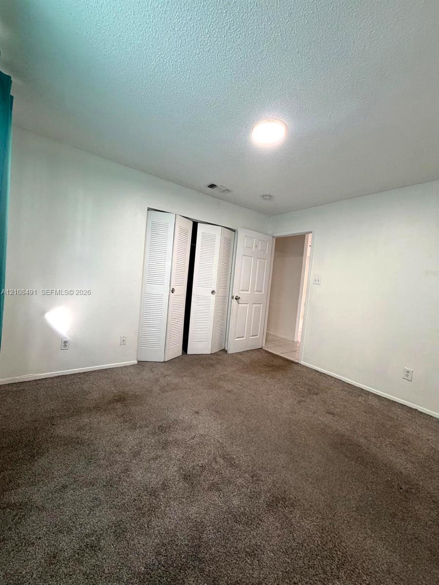 Room featuring neutral-toned carpeting, bi-fold louvered closet doors, and a paneled interior door