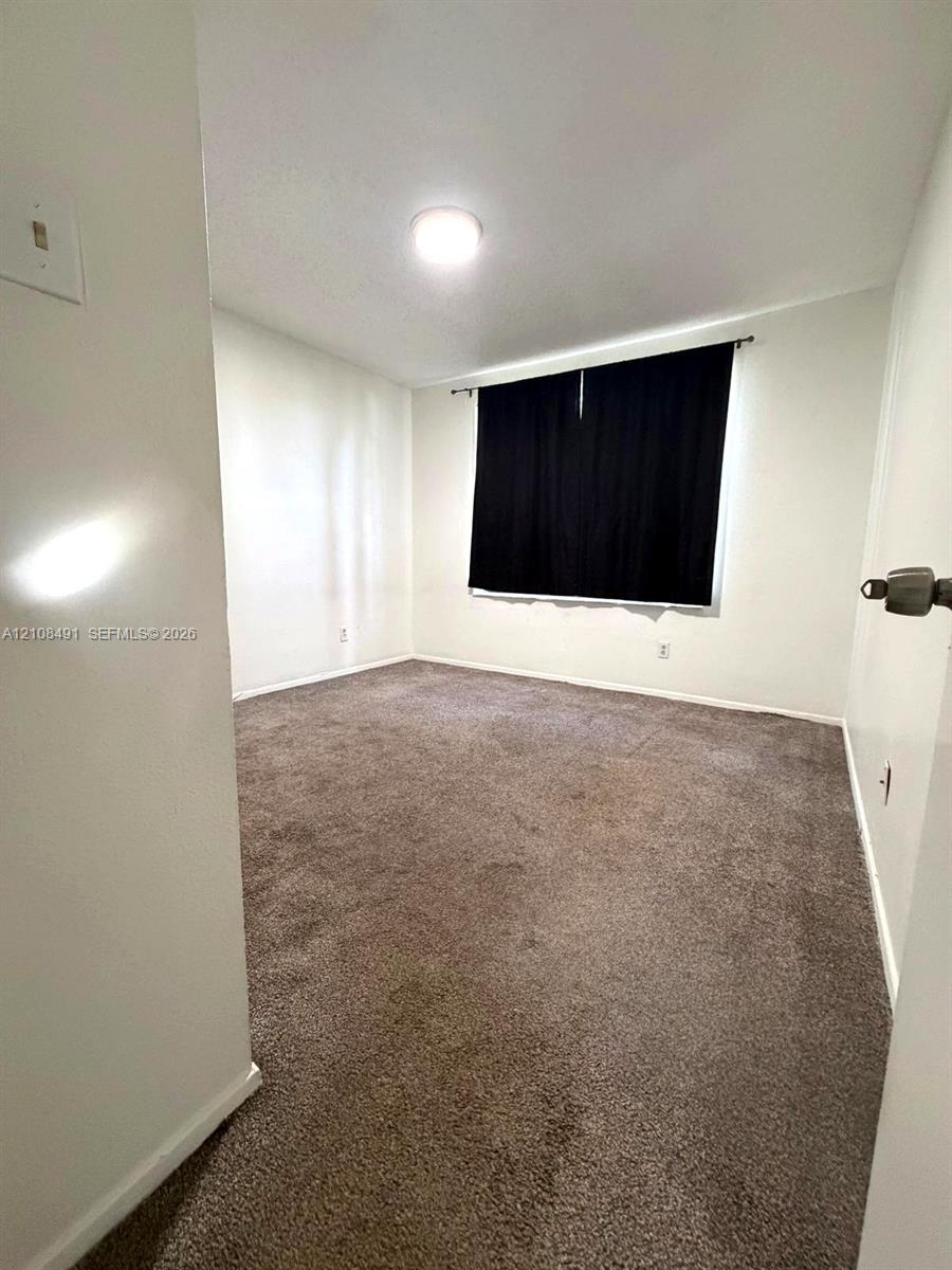 Neutral interior featuring wall-to-wall carpeting and a ceiling-mounted light fixture