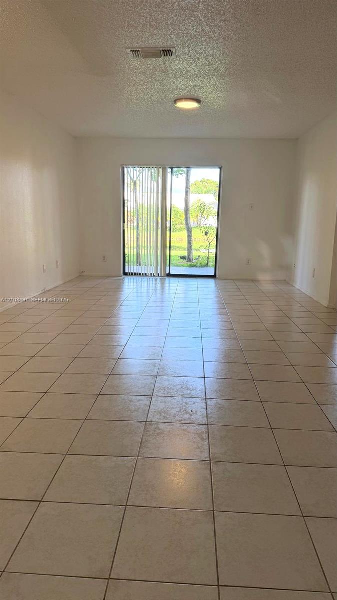 Neutral-toned tile flooring, sliding glass door, and flush-mount ceiling lighting Neutral-toned tile flooring, sliding glass door, and flush-mount ceiling lighting