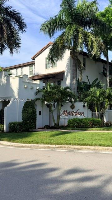 Stucco exterior facade featuring a multi-story profile, tiled roofline, and integrated signage, complemented by mature palm trees and manicured landscaping