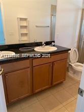 Bathroom vanity featuring a dark countertop, dual drop-in sinks, wooden cabinetry, built-in shelving, and tile flooring