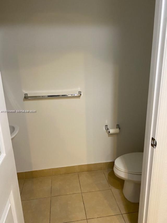 Restroom featuring large-format tile flooring, a wall-mounted towel bar, and a dedicated tissue holder