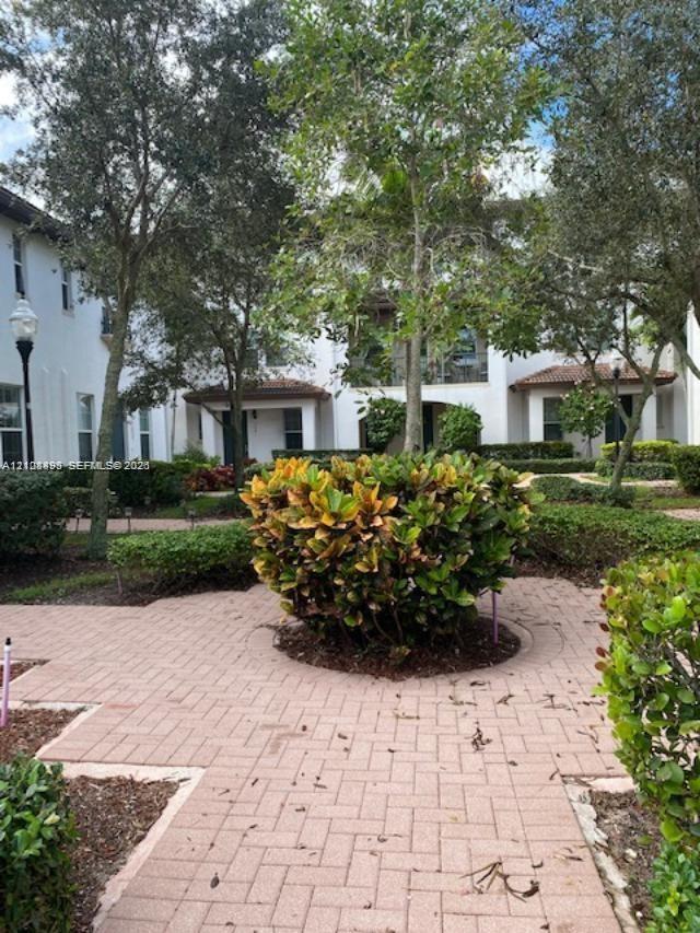 Exterior courtyard featuring herringbone-patterned brick pavers, mature landscaping, and light posts