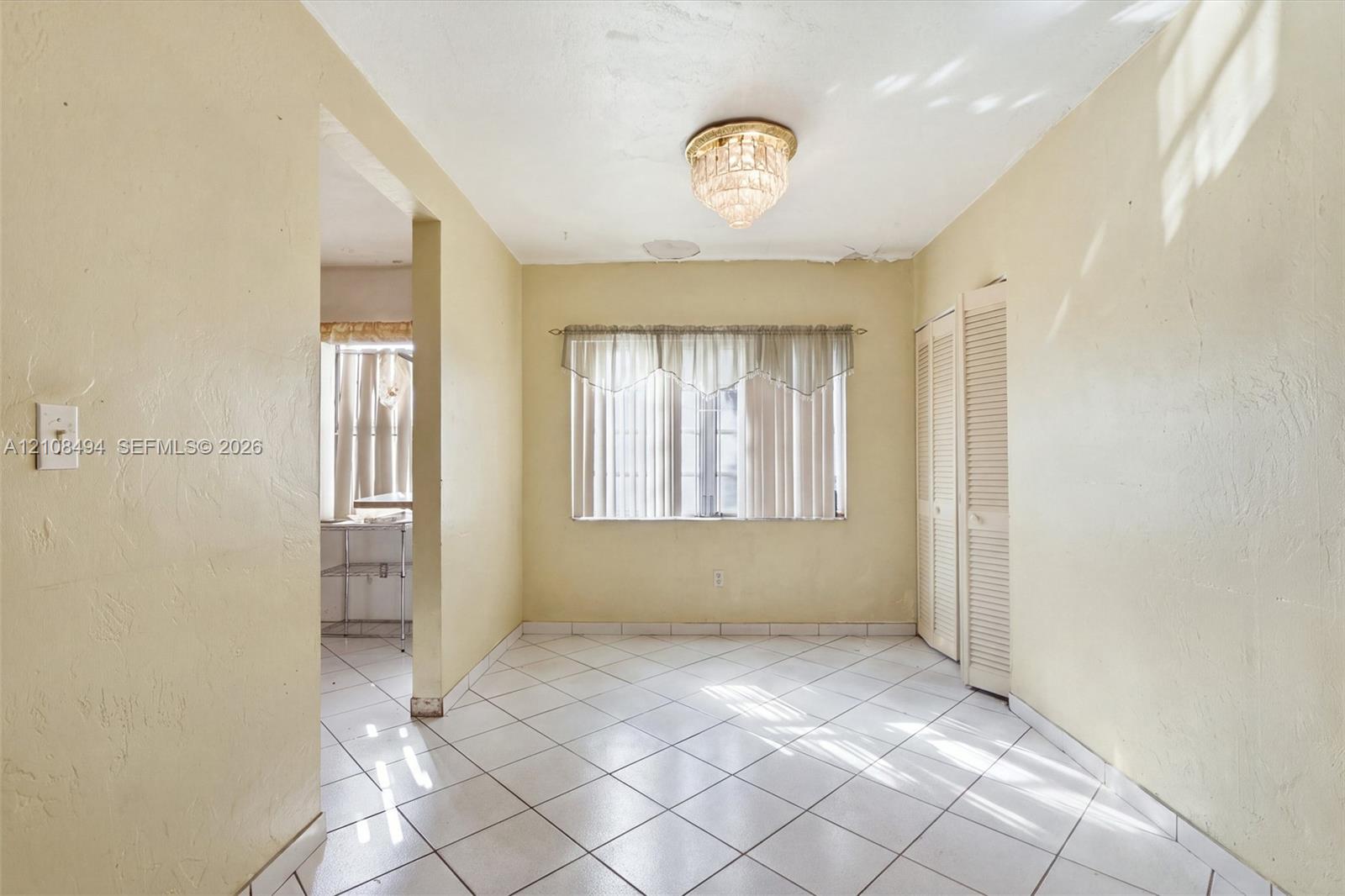 Neutral tile flooring, built-in louvered closet doors, and decorative crystal-style flush mount ceiling lighting Neutral tile flooring, built-in louvered closet doors, and decorative crystal-style flush mount ceiling lighting