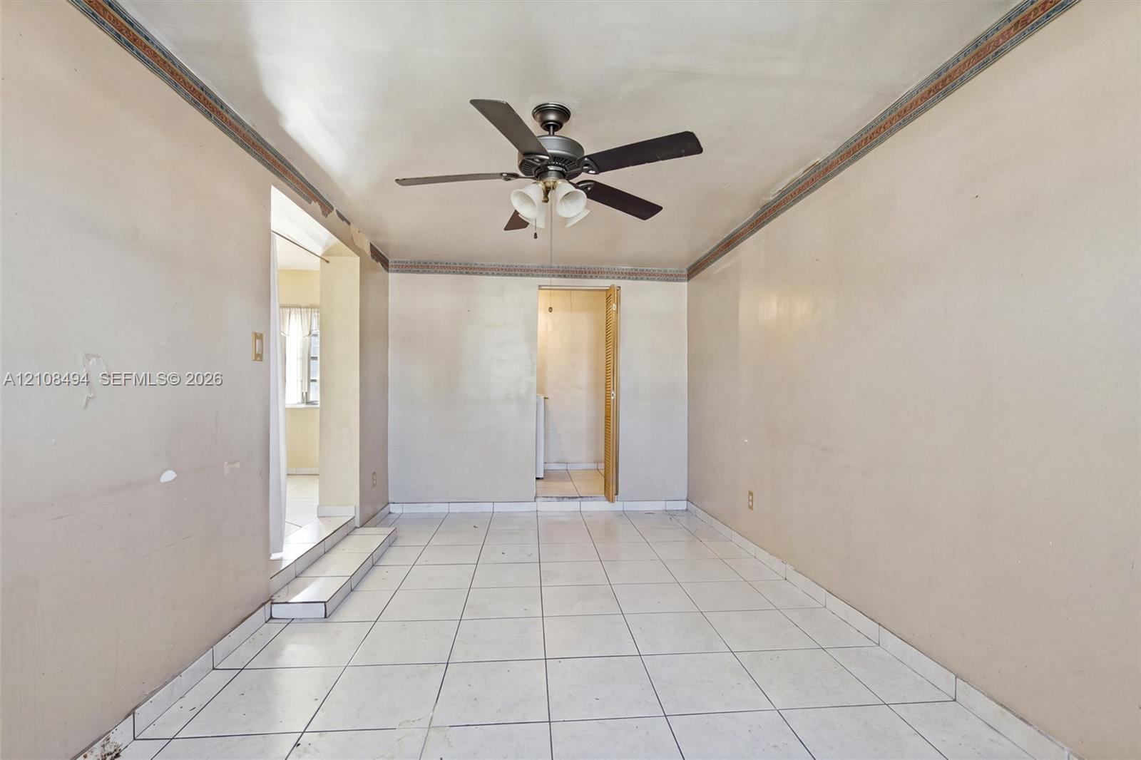 Interior space featuring white tile flooring, ceiling fan with integrated lighting, and decorative crown molding