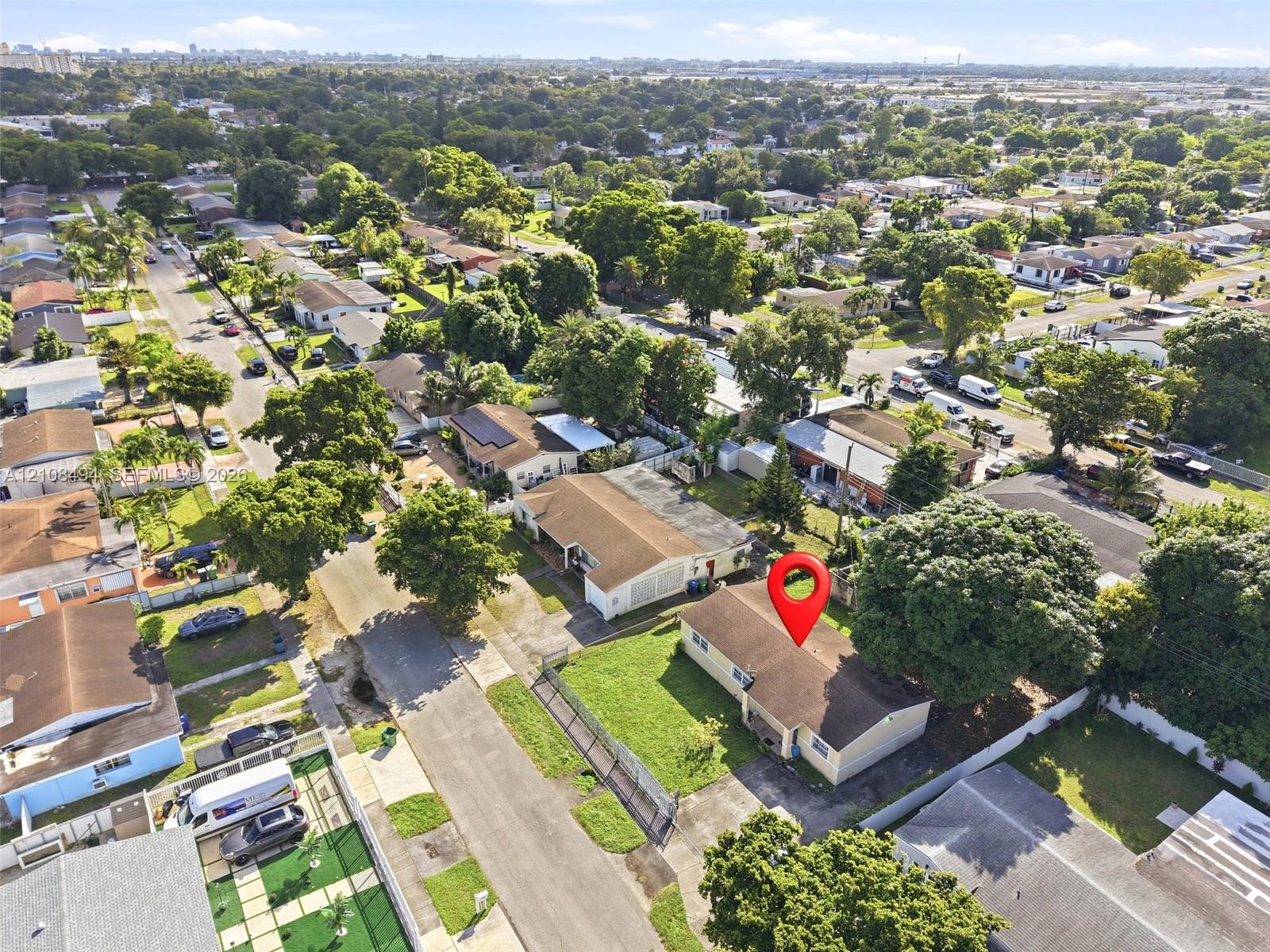 Aerial perspective of a single-story residence featuring a shingled roof, a concrete driveway, and established trees within a residential neighborhood