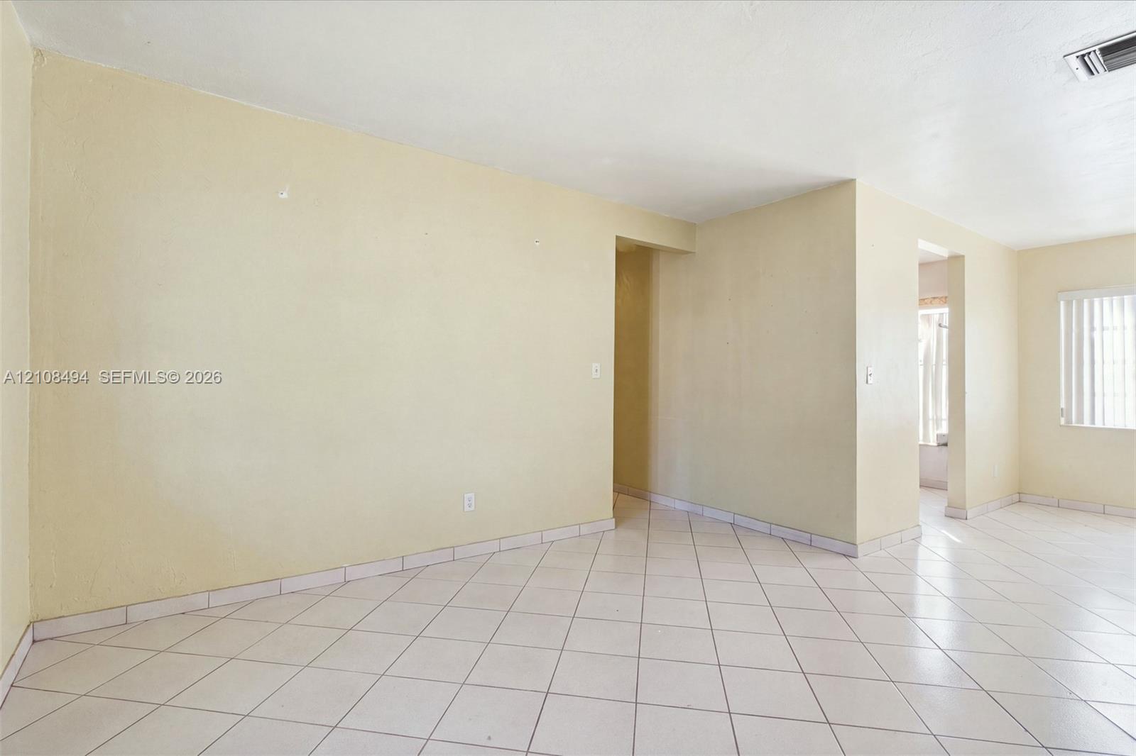 Interior space featuring neutral-toned walls, tile flooring set on a diagonal pattern, and vertical slat window blinds Interior space featuring neutral-toned walls, tile flooring set on a diagonal pattern, and vertical slat window blinds