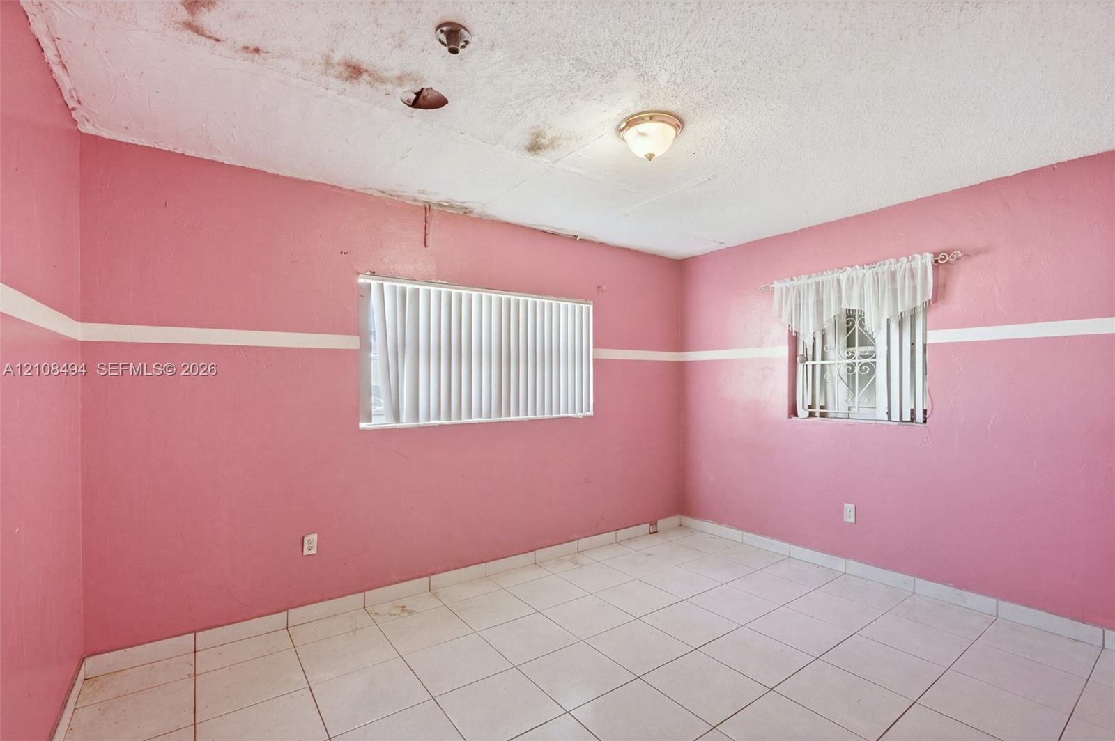 Tile flooring throughout featuring two windows with horizontal blinds and an attached ceiling-mounted light fixture