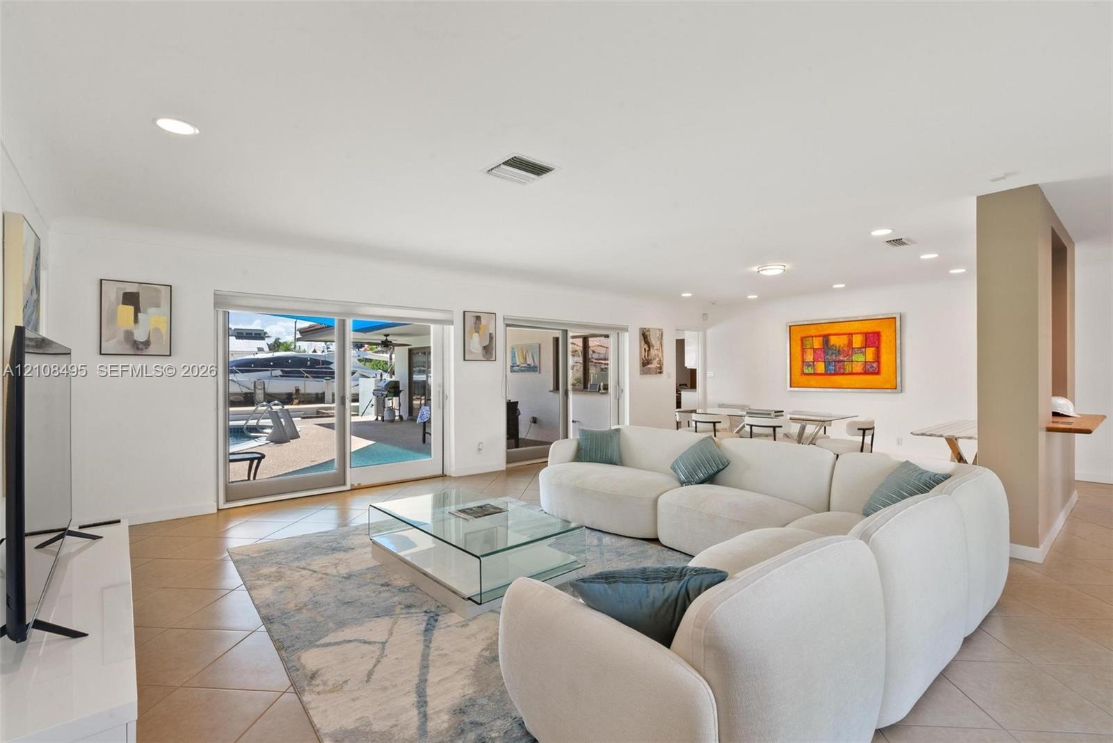 Open-concept living space featuring neutral tile flooring, recessed ceiling lighting, and expansive dual sliding glass doors