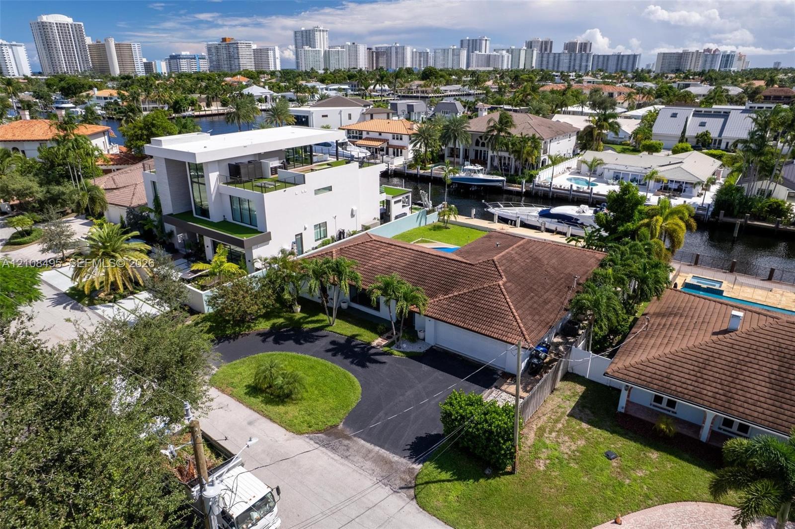 Waterfront property featuring a tile roof, paved driveway, swimming pool, and private boat dock