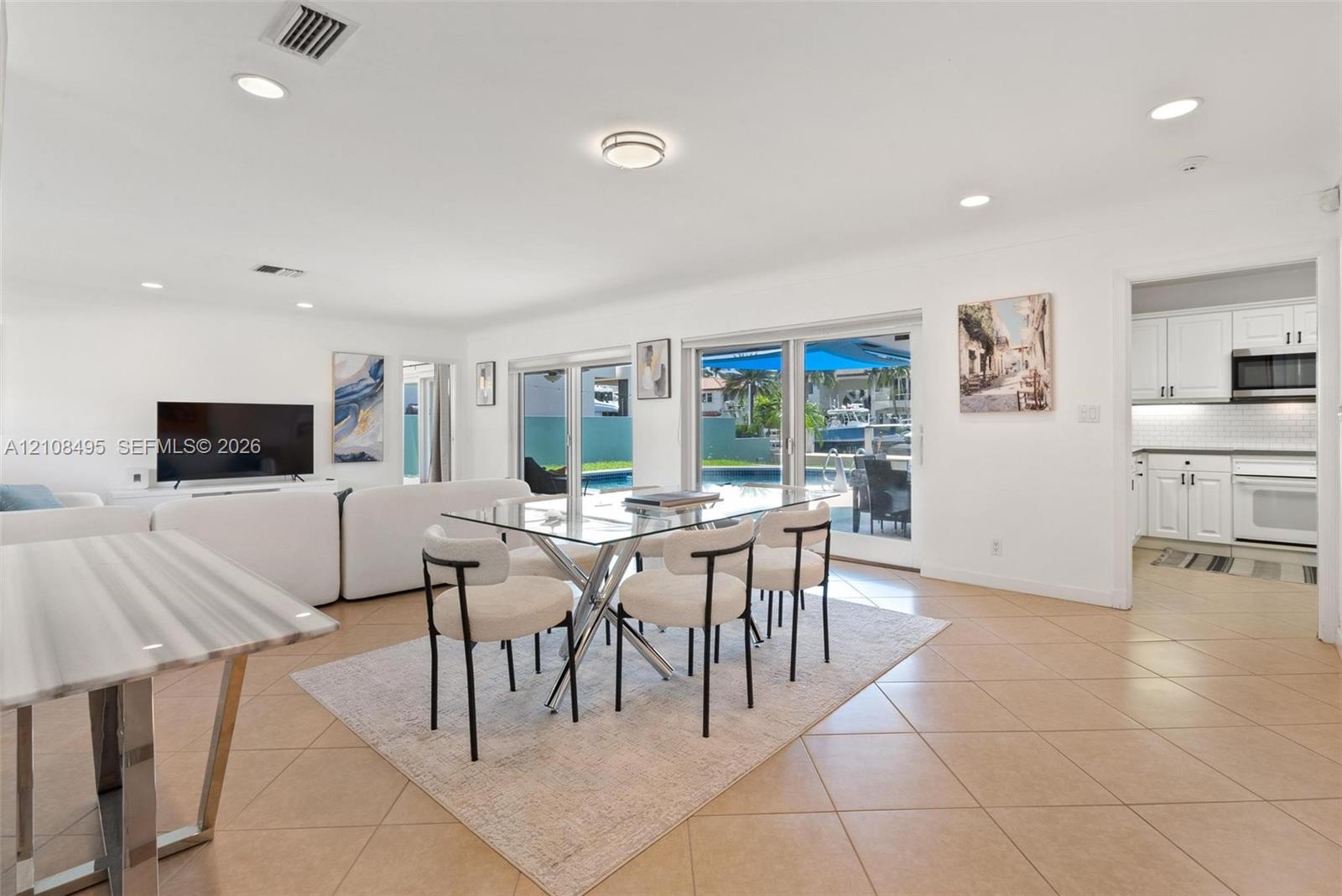 Open-concept interior featuring large-format tile flooring, recessed lighting, and multiple sliding glass doors providing outdoor access