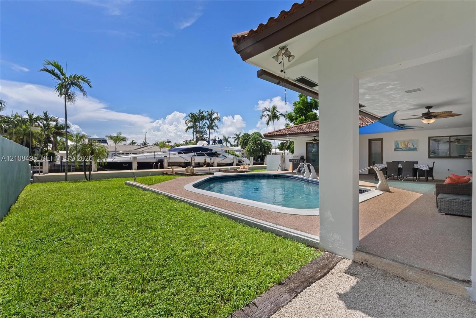 Covered patio with recessed lighting and ceiling fan, swimming pool with aggregate decking, and direct bulkhead access