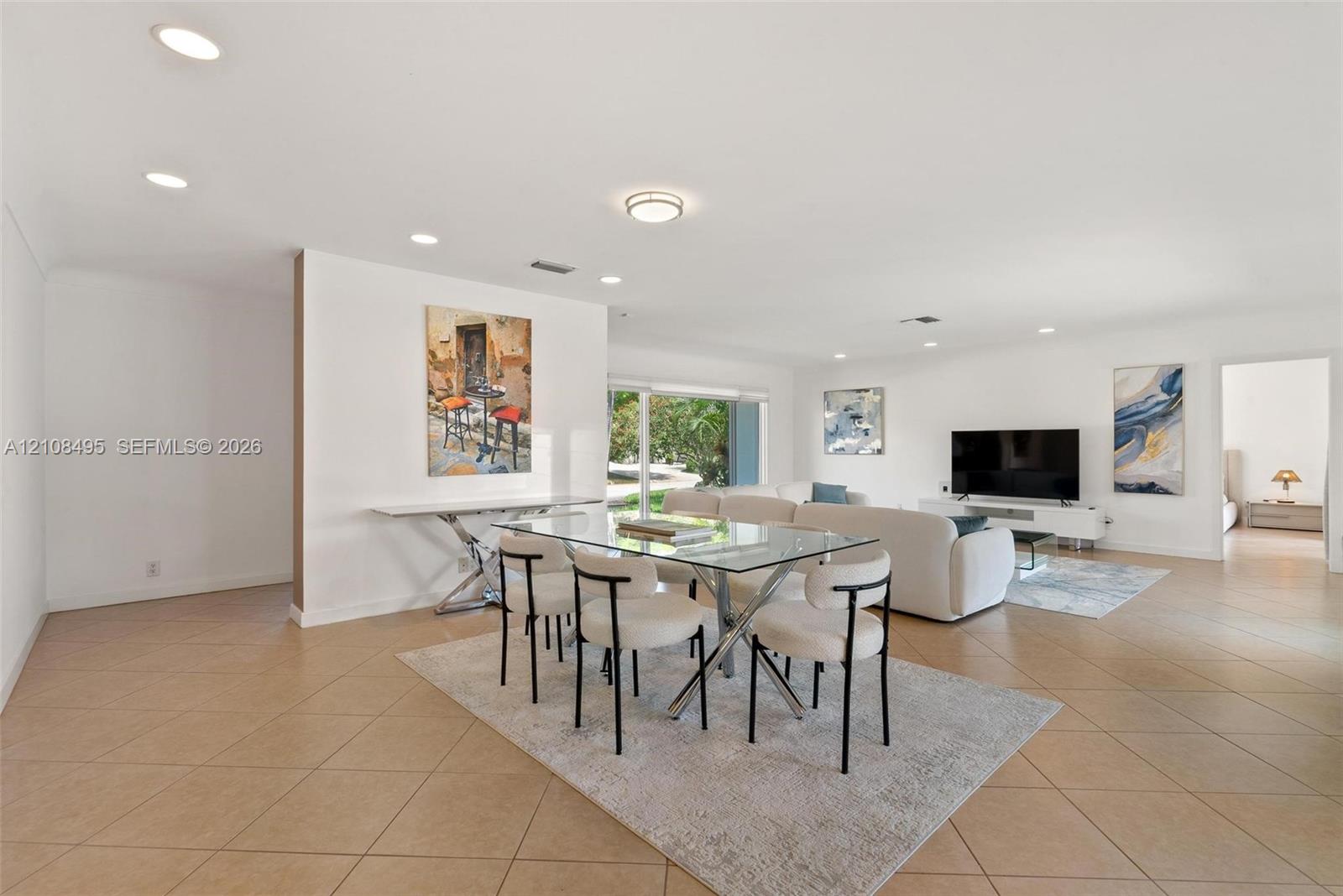 Open-concept living space featuring neutral ceramic tile flooring, recessed lighting, and large glass sliding doors