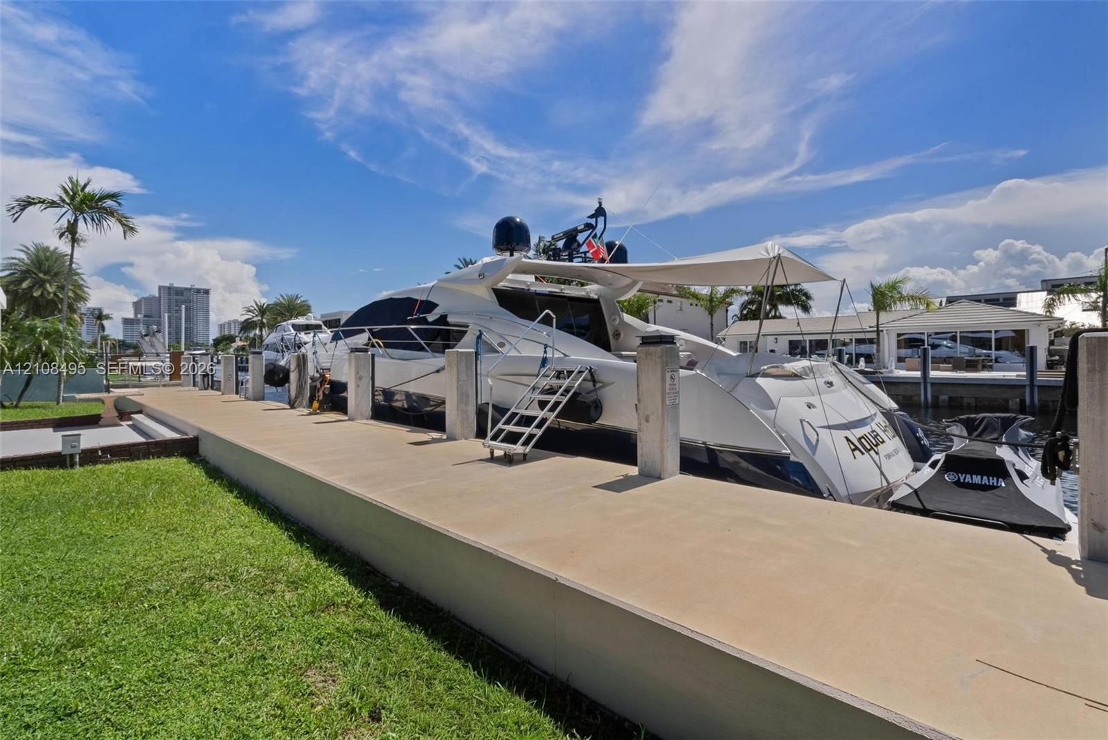 Concrete dock featuring built-in pilings, manicured turf bordering the water, and direct access to a deep-water canal