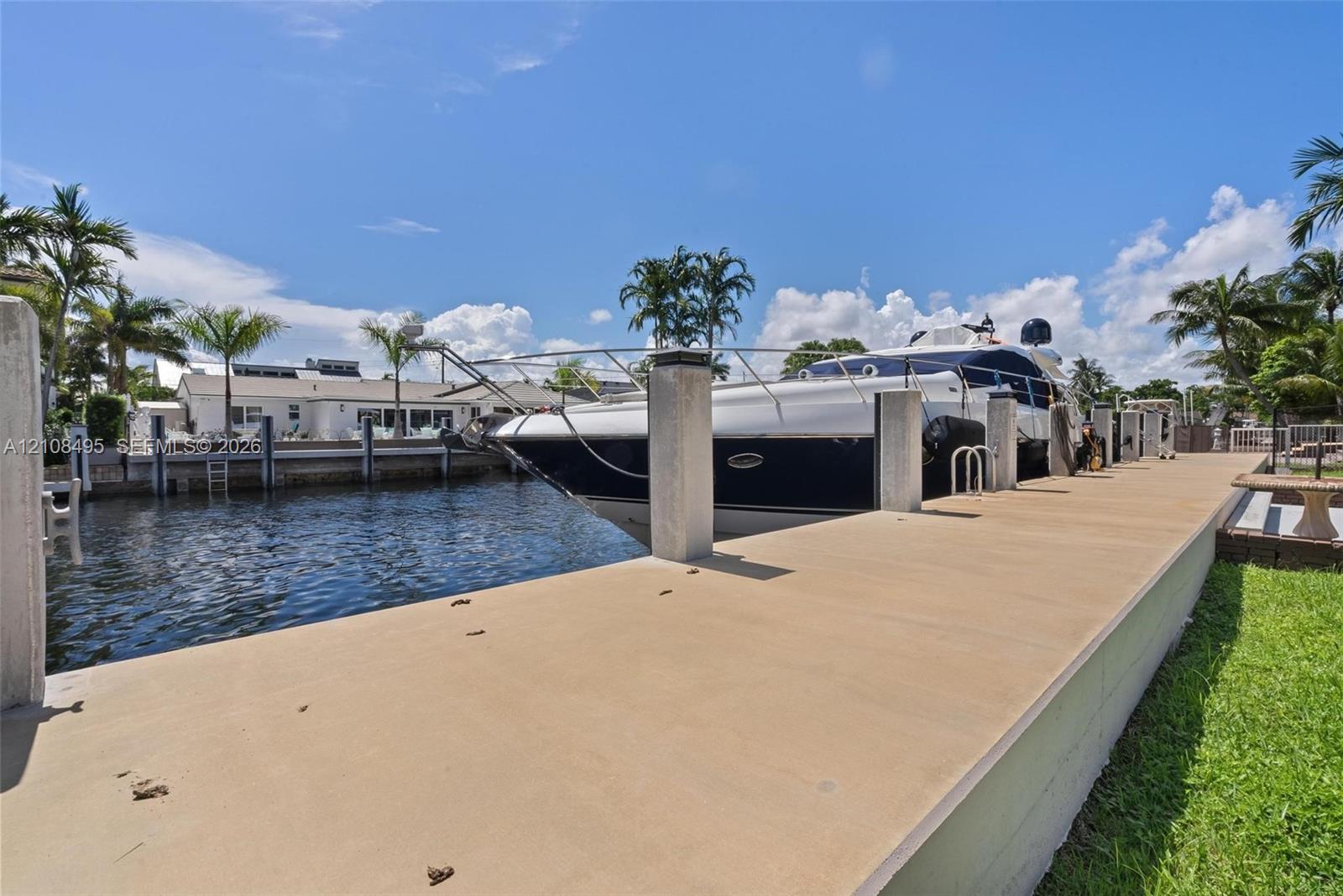Concrete deep-water dock featuring multiple pilings, integrated ladder access, and manicured grass perimeter