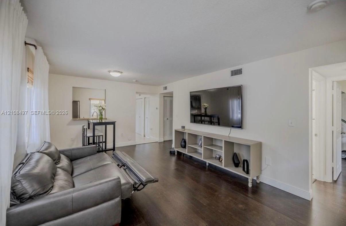 Living area featuring dark wood-finish flooring, neutral wall tones, a recessed wall niche, and an interior pass-through window with a ledge