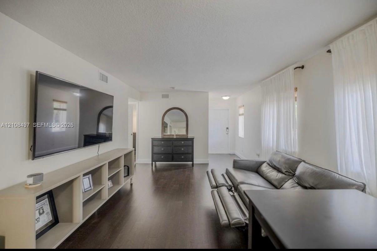 Living space featuring wood-finish flooring, white walls, and built-in shelving
