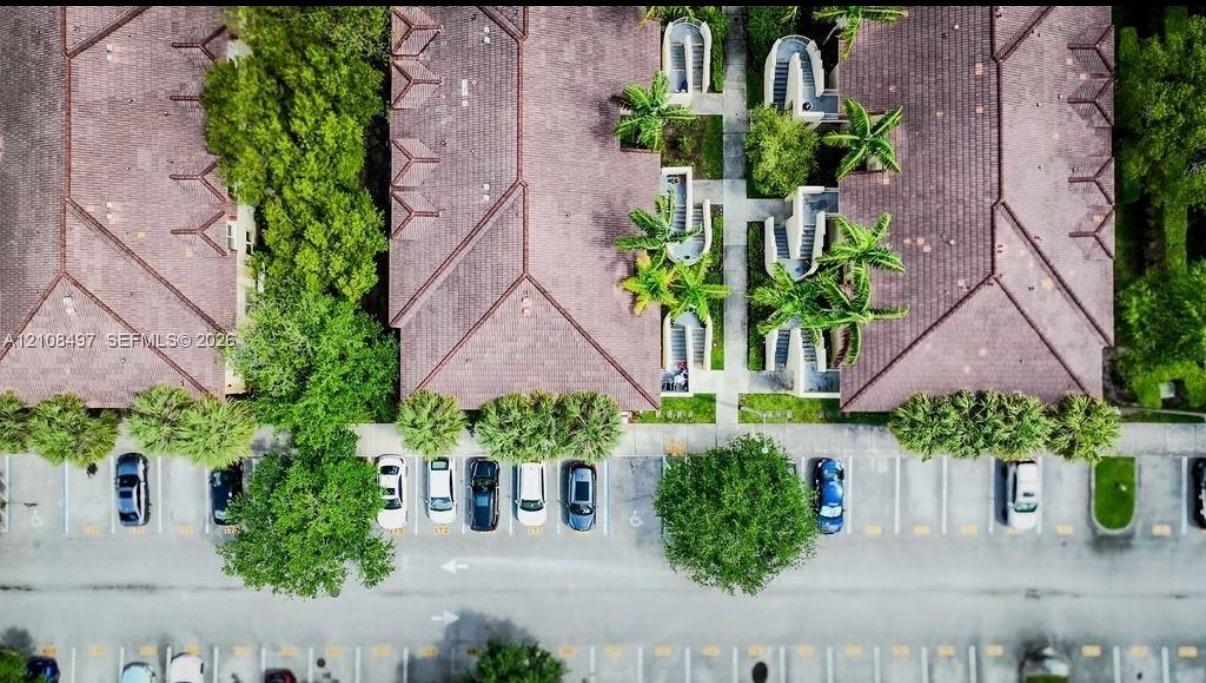 Aerial perspective featuring tile-roofed buildings, paved parking surfaces, dedicated pedestrian walkways, and mature landscaping